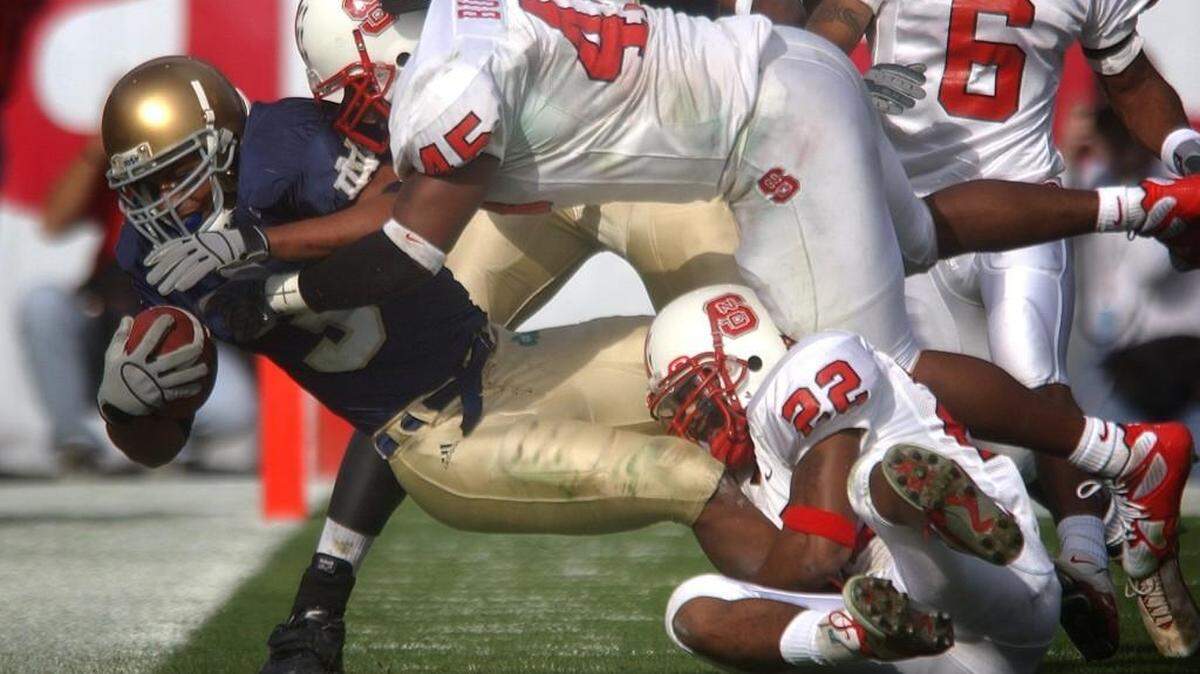 N.C. State's Dantonio Burnette, top, and Gregory Golden take down Notre Dame's Arnaz Battle during the Gator Bowl at Alltel Stadium in Jacksonville, Fla., in 2003. The Wolfpack beat the Irish 28-6.