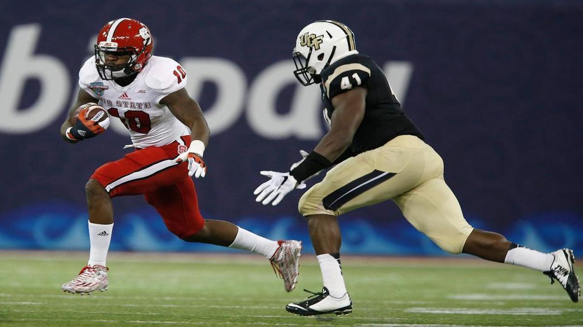 
N.C. State running back Shadrach Thornton looks for running room as UCF linebacker Terrance Plummer closes in during the Wolfpack’s Bitcoin St. Petersburg Bowl win on Dec. 26, 2014.
