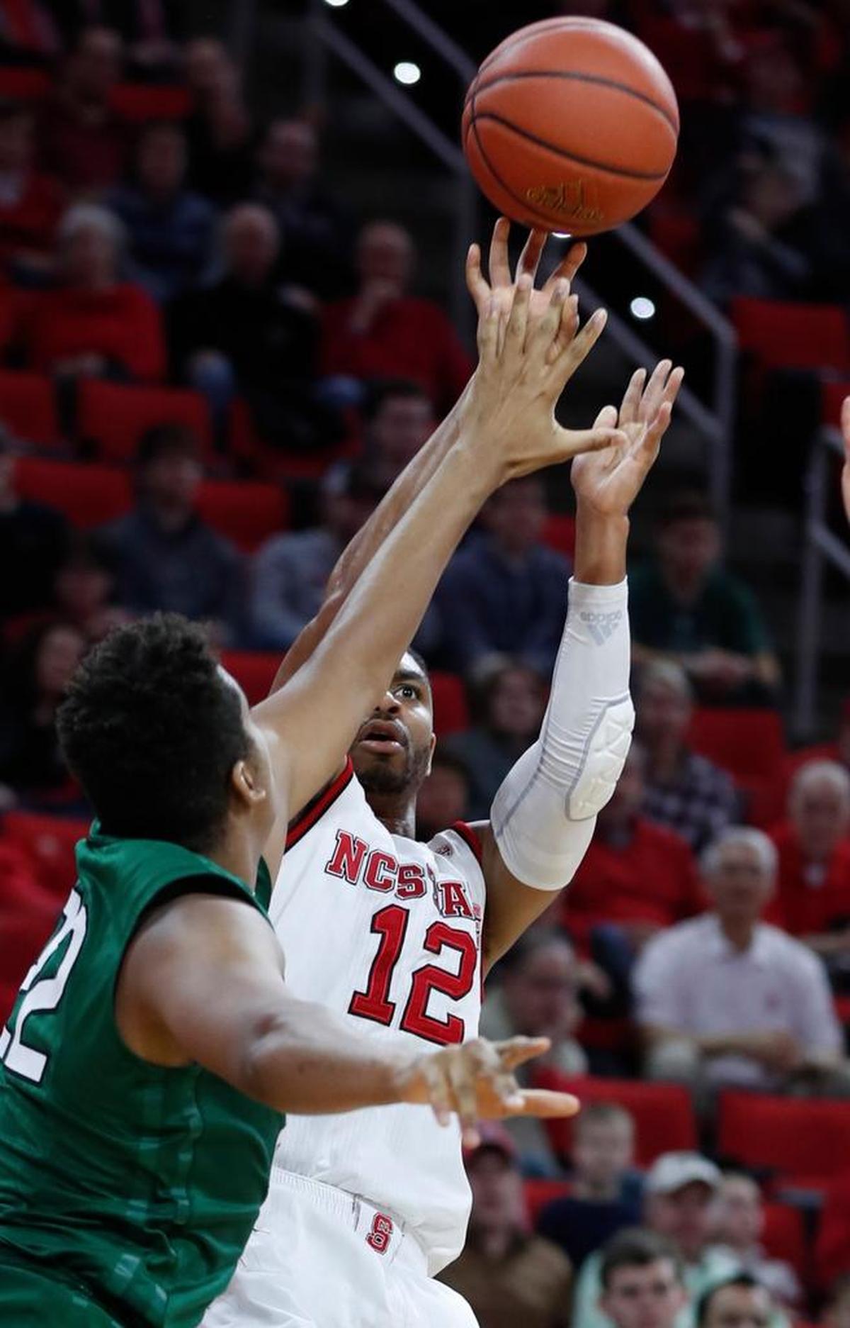 N.C. State's Allerik Freeman (12) shoots as Jacksonville's Radwan Bakkali (22) defends at PNC Arena Friday, Dec. 22, 2017.