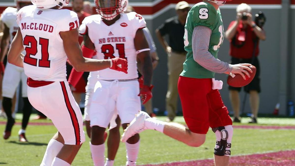 Wolfpack QB Ryan Finley (15) smiles as he runs into the end zone against Nick McCloud (21) and Jarius Morehead (31) during Kay Yow N.C. State Red- White intra-squad spring football game played at Carter-Finley Stadium on April 1, 2017