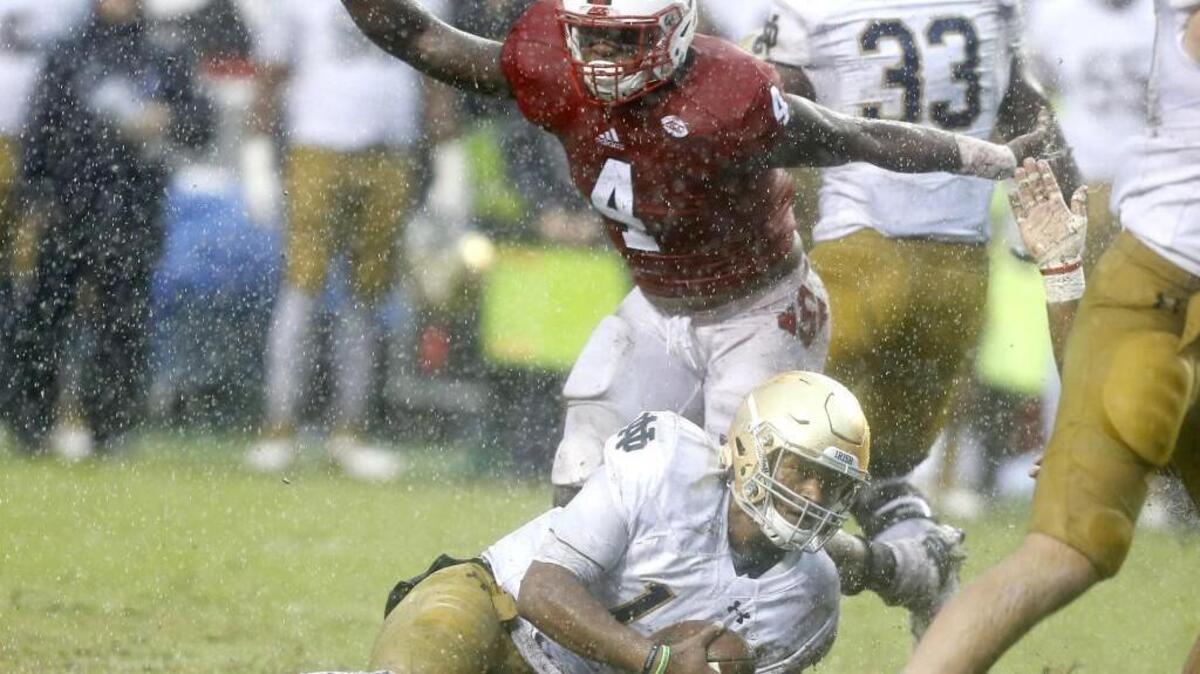 N.C. State linebacker Jerod Fernandez, middle, celebrates after Notre Dame quarterback DeShone Kizer, bottom, was sacked on Oct. 8. The ACC announced an extended football agreement with the Fighting Irish.