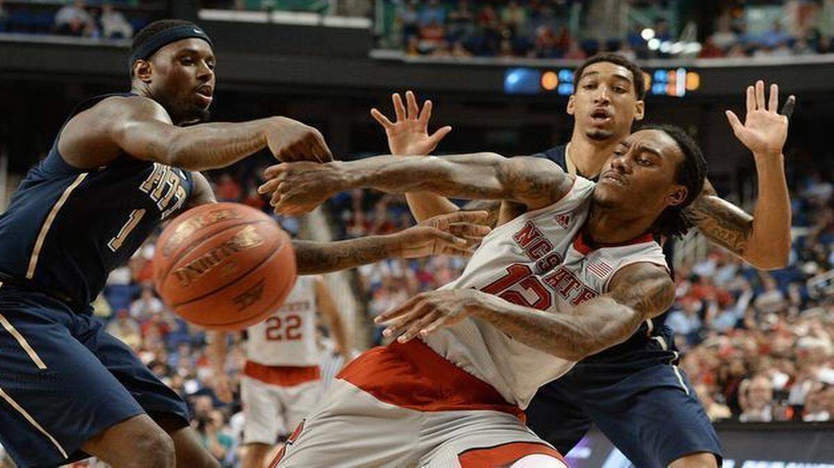 
N.C. State’s Cat Barber passes out of a double team by Pitt’s Jamel Artis (1) and Cameron Wright in the second half of play in the second round of the ACC Tournament at the Greensboro Coliseum.
