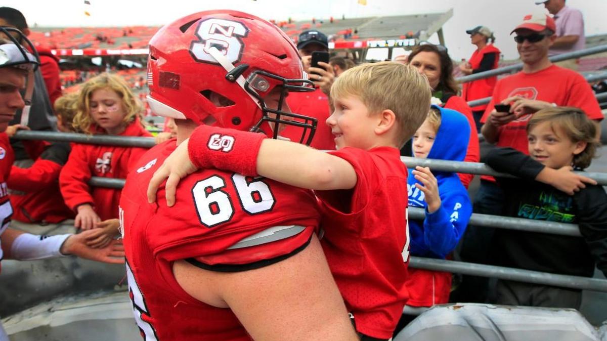 N.C. State center Joe Scelfo gives his cousin, Torr Scelfo, 6, a hug after Miami’s 27-13 victory over the Wolfpack at Carter-Finley Stadium on Nov. 19. It is the last game at Carter-Finley for Scelfo.