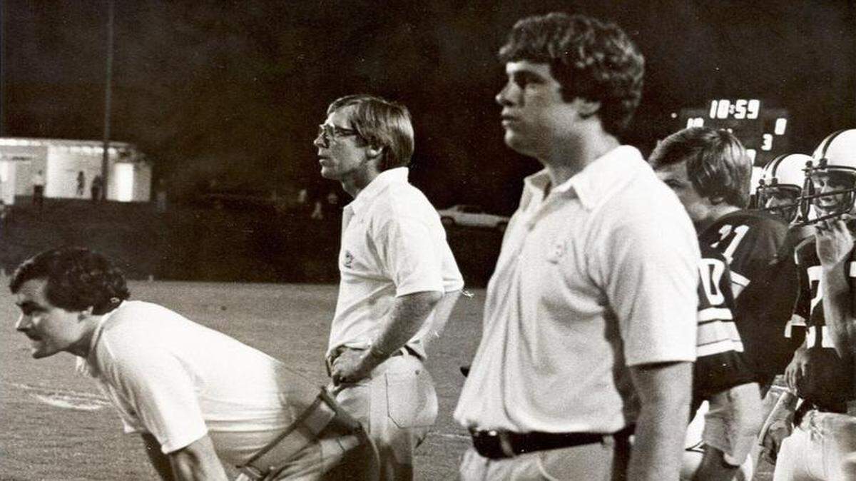 Dick Sheridan, middle, and Ken Pettus, left, work on the sideline as coaches at Furman.