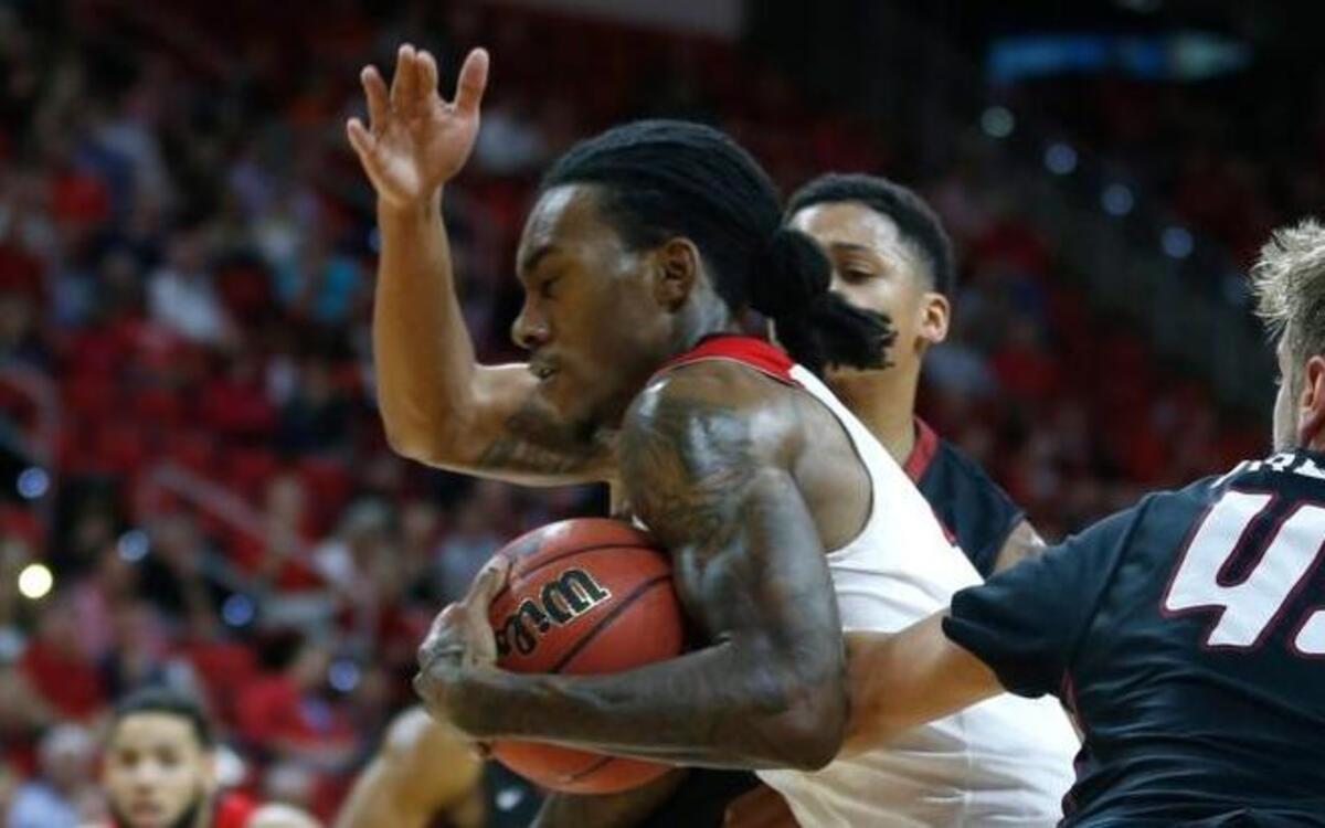 N.C. State's Cat Barber (12) is fouled as he drives around IUPUI's Aaron Brennan (45), right, and T.J. Henderson (1) during the first half of the Wolfpack's game against IUPUI at PNC Arena in Raleigh, N.C., Wednesday, Nov. 18, 2015.