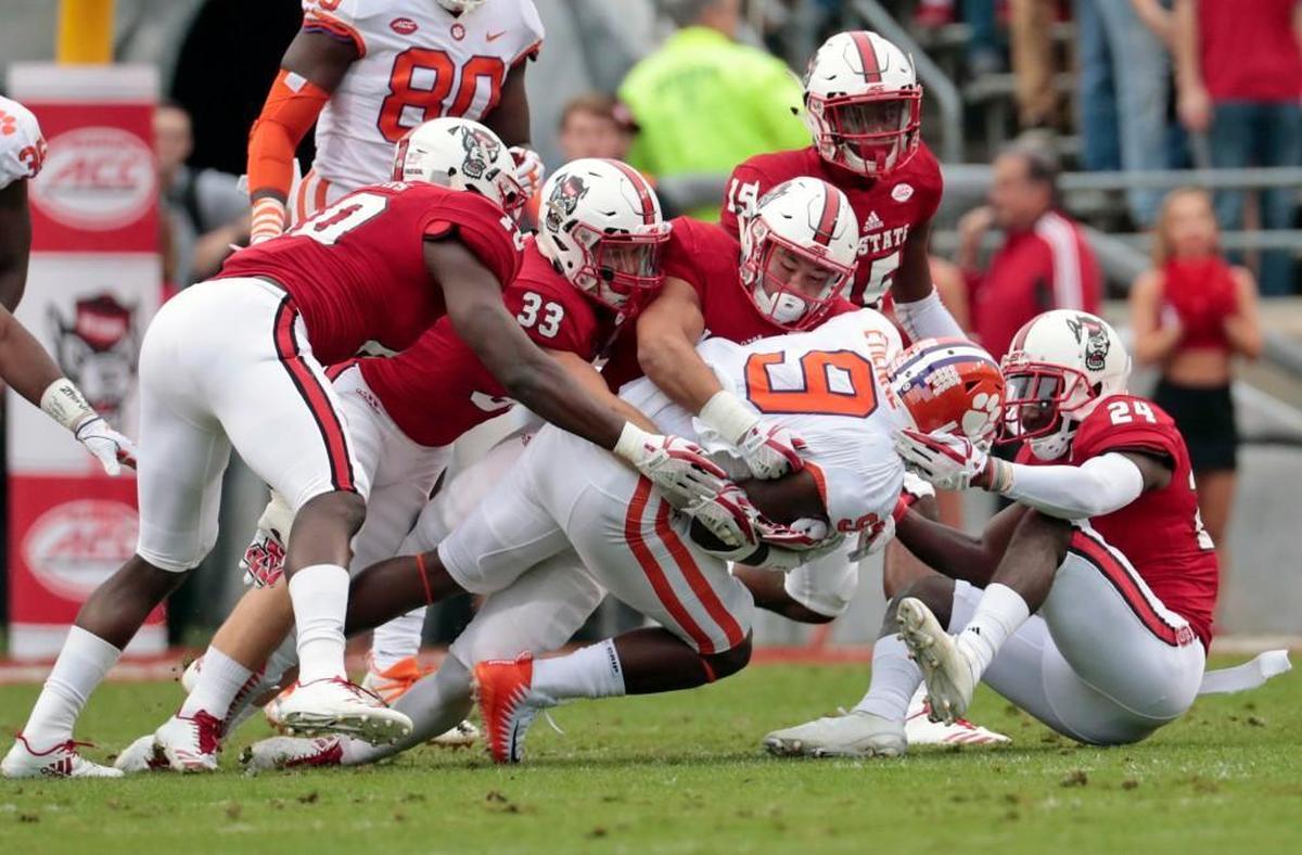 NCSU's Louis Acceus (10) Brady Bodine (33) and Shawn Boone (24) gang-tackle Clemson's Travis Etienne (9) during the first quarter of an ACC college football game between the N.C. State Wolfpack and the Clemson Tigers played at Carter-Finley Stadium in Raleigh, NC on Nov. 4, 2017.