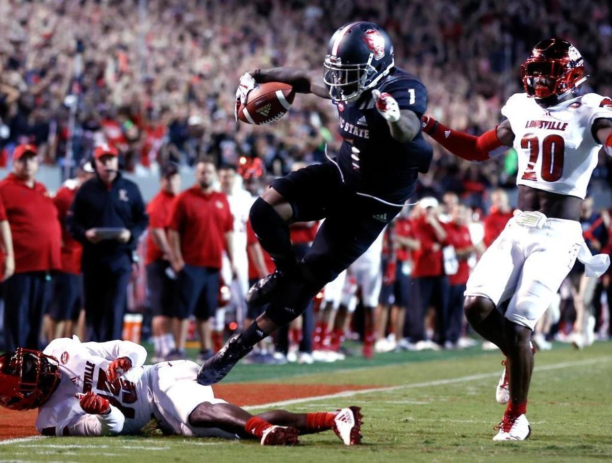 N.C. State’s Jaylen Samuels (1) hurdles over Louisville’s Trumaine Washington (15) as Ronald Walker (20) also defends at the end of Samuels’ 79-yard run during the Wolfpack’s victory at Carter-Finley Stadium.