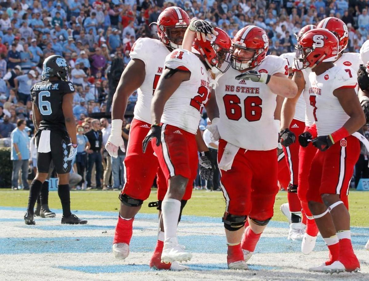 N.C. State’s Joe Scelfo (66) celebrates with Matt Dayes (21) after Dayes scored on a 18-yard touchdown run during the Wolfpack’s 28-21 victory over UNC at Kenan Stadium on Nov. 25, 2016.