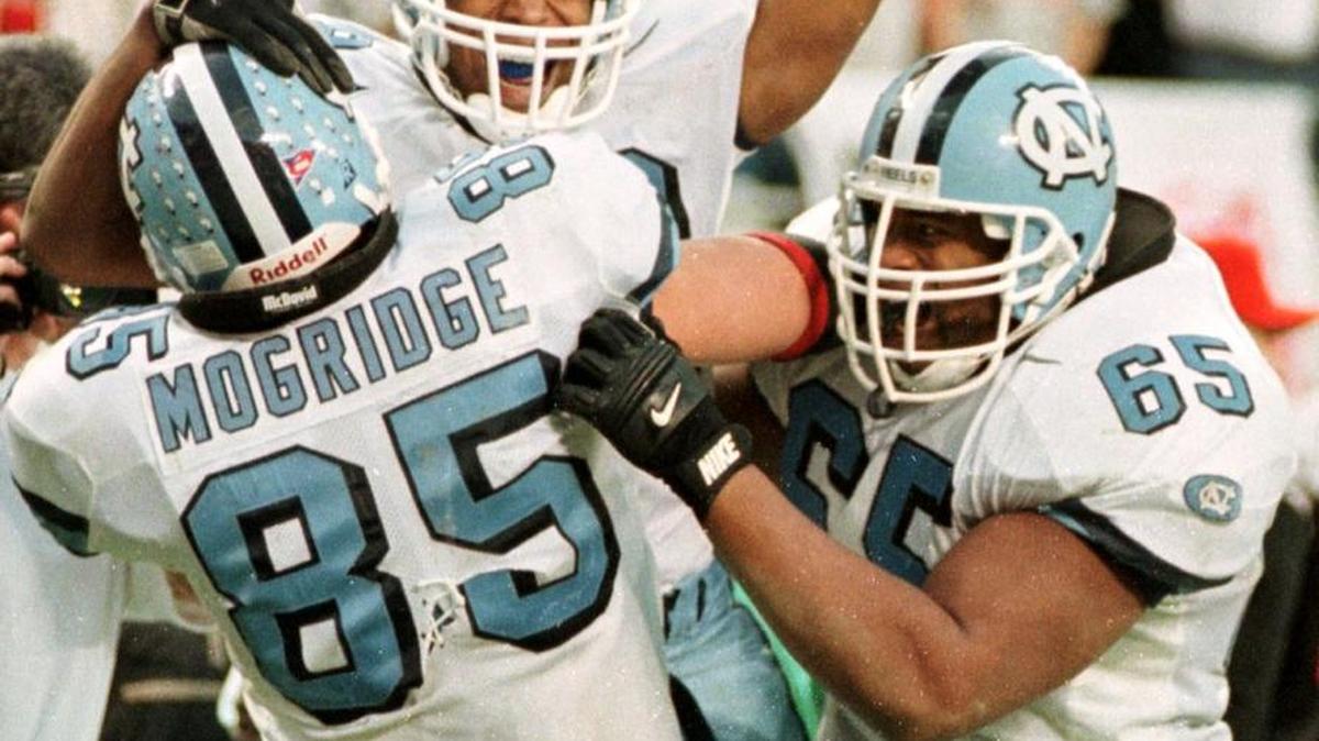 UNC's (18) Na Brown celebrates with his teammates (85) Allen Mogridge and (65) Kareem Ellis after Brown caught the winning TD to defeat NCSU in overtime.