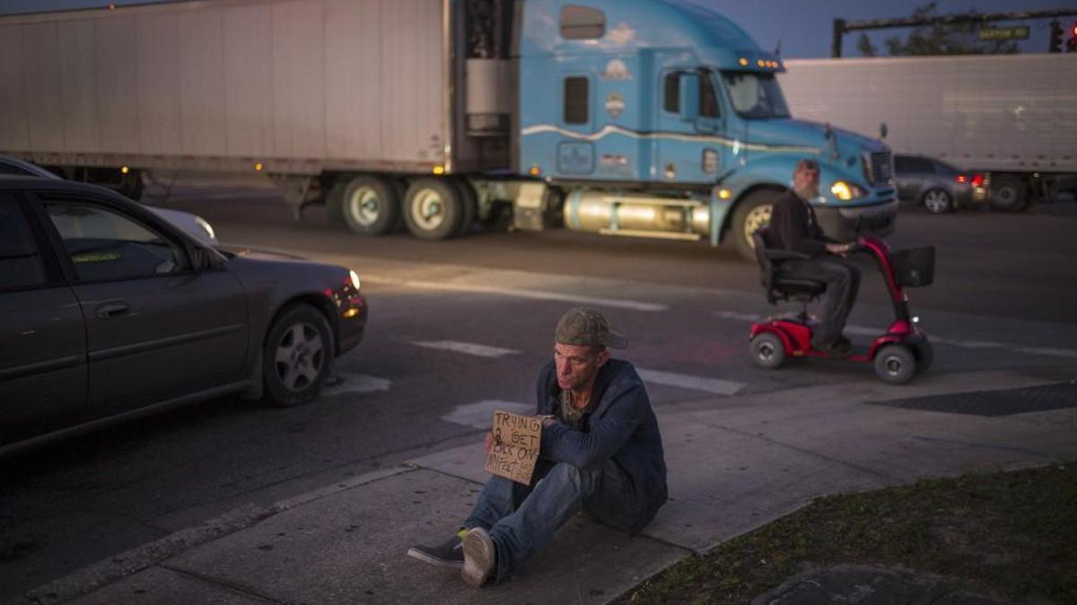 Ryan Hoffman with a panhandling sign that reads “Trying 2 get back on my feet, God bless” at a busy intersection in Lakeland, Fla., Jan. 7, 2015. Hoffman, once a 287-pound starting left tackle for a top-ten ranked University of North Carolina football team, died Nov. 16 after struggling with addiction and memory problems and living on the streets.