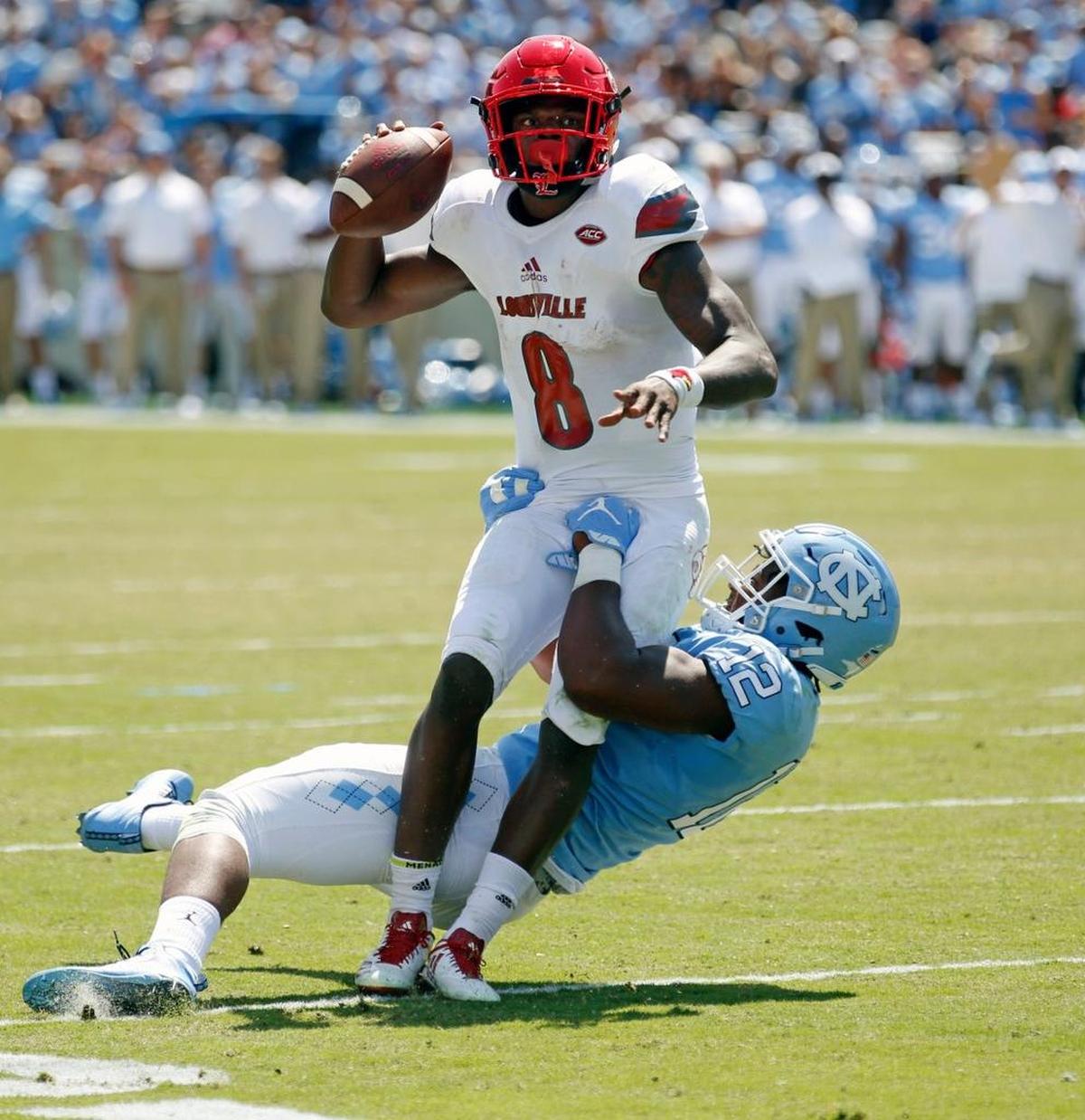 Louisville's Lamar Jackson (8) evades a tackle attempt by UNC's Tomon Fox (12) during the second quarter in a game between UNC and Louisville at Kenan Stadium in Chapel Hill on Sept. 9, 2017.