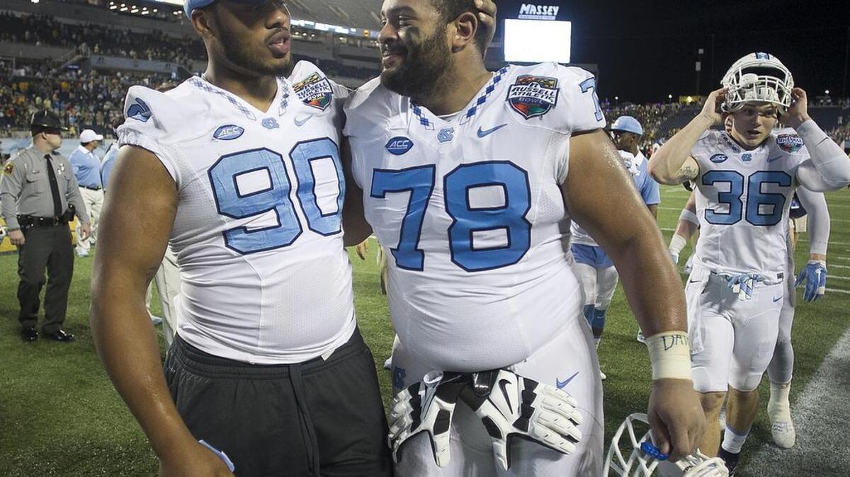 North Carolina senior Landon Turner (78) is embraced by teammate Nazir Jones (90) following their 49-38 loss to Baylor.