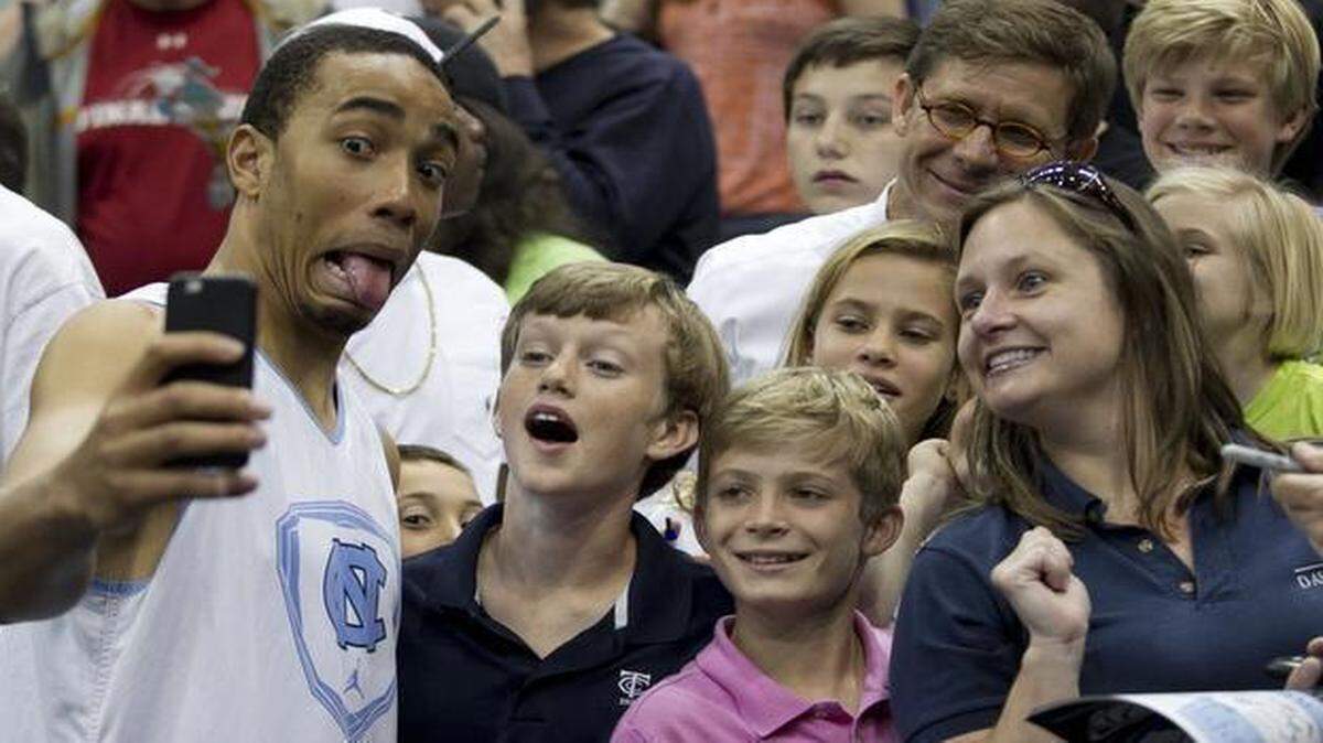 
North Carolina’s Brice Johnson enjoys posing for a photograph with a family after practice Wednesday in Jacksonville, Fla.  Coach Roy Williams encouraged his players to go into the seating area to greet fans. The Tar Heels will play Harvard on Thursday night. 
