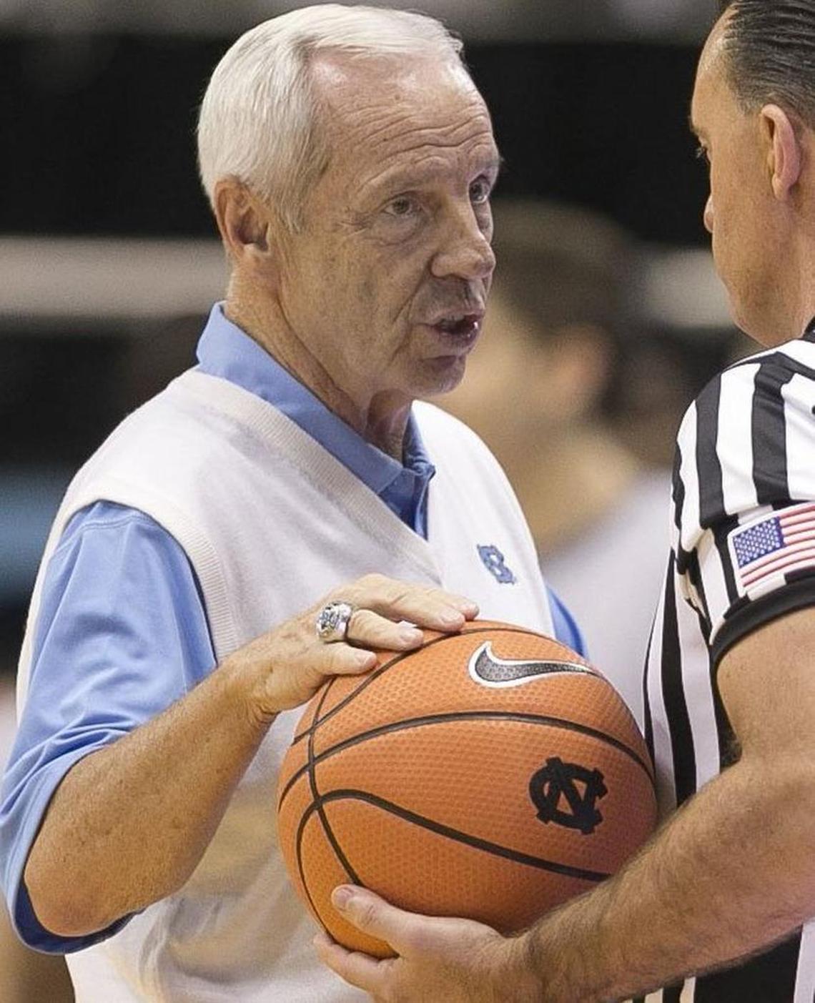 North Carolina coach Roy Williams talks with official Roger Ayers. The Nike swoosh logo adorns everything from the basketballs, clothing, uniforms, and shoes.