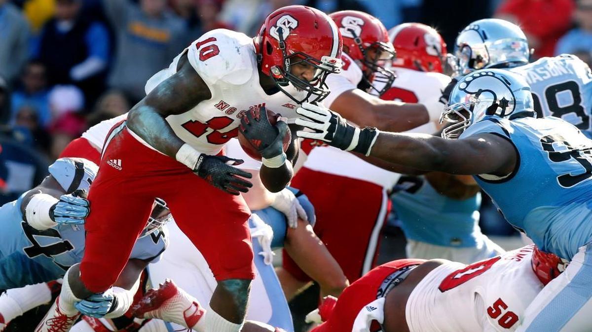 
N.C. State running back Shadrach Thornton (10) beats UNC defensive end Junior Gnonkonde (44), left, and defensive tackle Ethan Farmer (96) on a four-yard touchdown run during the first half of the Wolfpack's game against North Carolina at Kenan Stadium in Chapel Hill, N.C., Saturday, Nov. 29, 2014.

