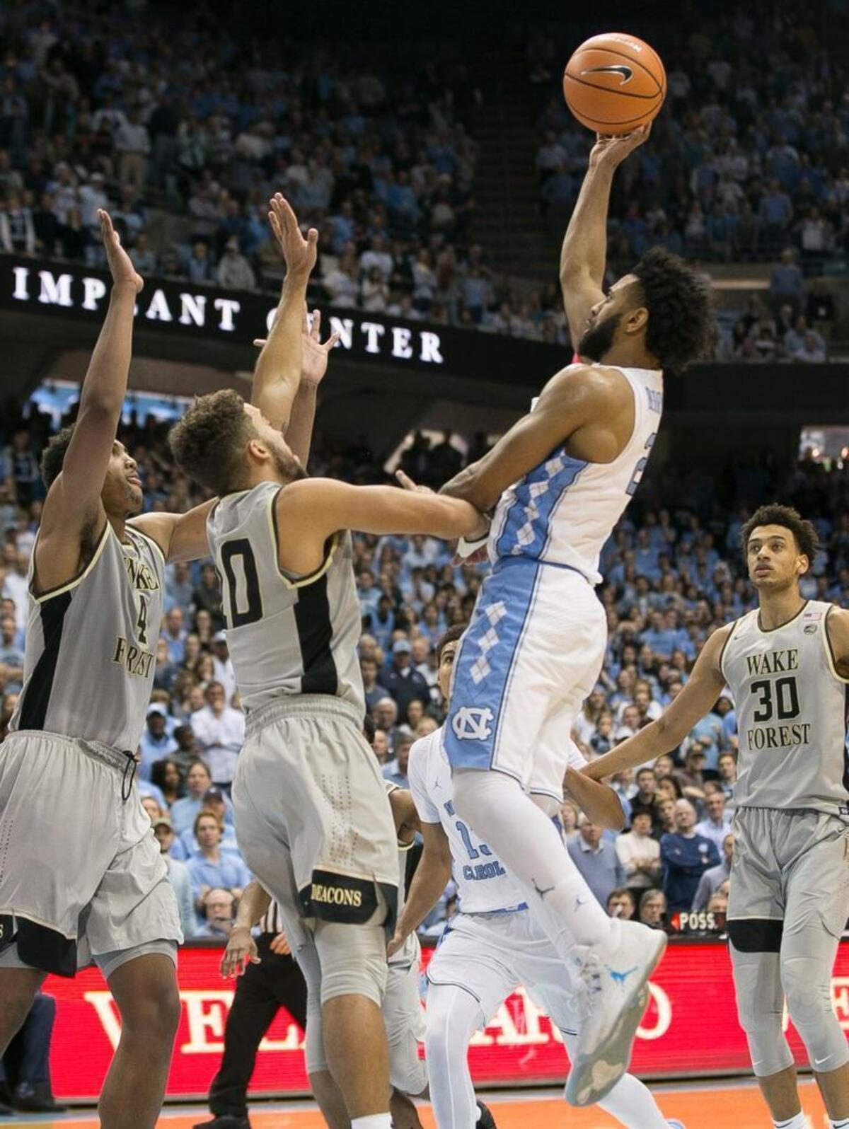 North Carolina’s Joel Berry II (2) drives to the basket against Wake Forest’s Doral Moore (4) and Mitchell Wilbekin (10) and puts up the game winning shot with :11 seconds to play to give the Tar Heels a 73-69 victory on Saturday, December 30, 2017 at the Smith Center in Chapel Hill, N.C.