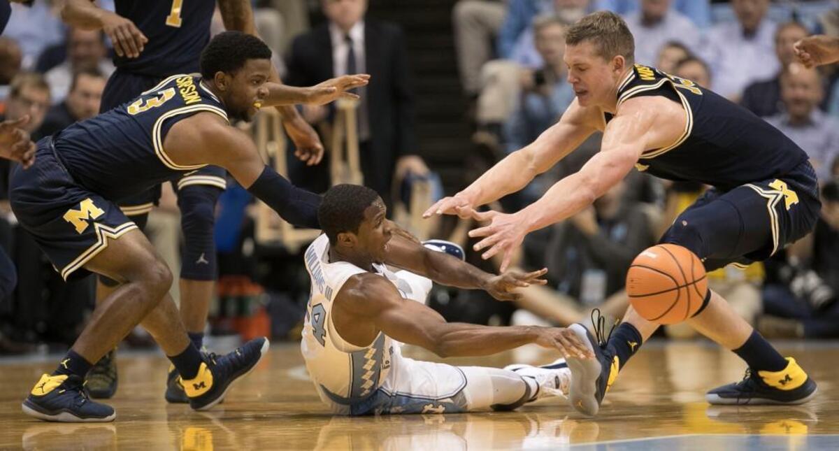 North Carolina’s Kenny Williams (24) hits the court to recover a loose ball between Michigan’s Zavier Simpson (3) and Mortiz Wagner (13) during the second half on Wednesday, November 29, 2017 at the Smith Center in Chapel Hill, N.C.