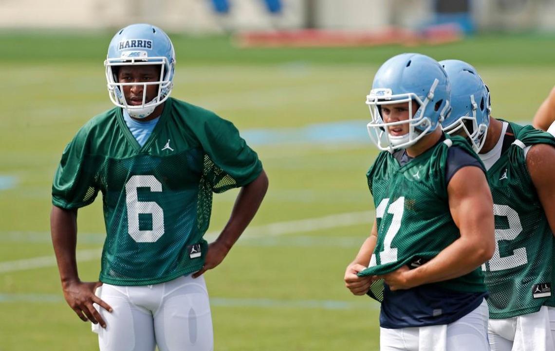 Quarterbacks Brandon Harris, left, and Nathan Elliott, right, listen to a coaches instructions during a drill at practice on Aug. 2.