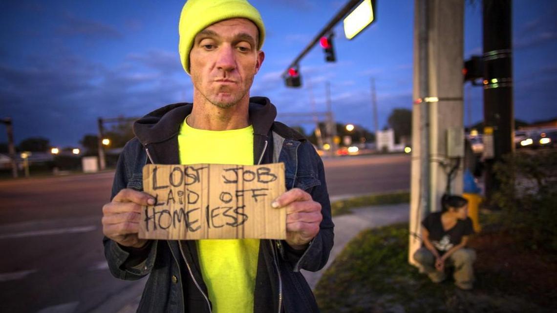 Ryan Hoffman with a panhandling sign and his girlfriend Michelle Pettigrew, in background, at a busy intersection in Lakeland, Fla., Jan. 7, 2015. Hoffman died Nov. 16 after he rode his bike into traffic and collided with an oncoming car.