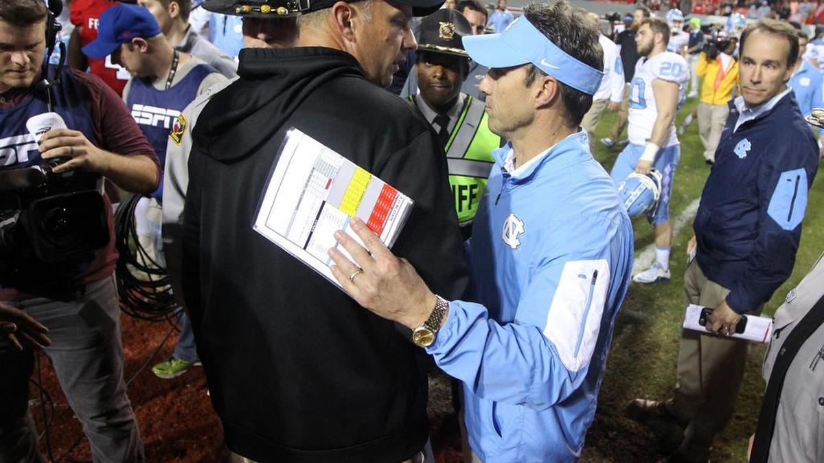 N.C. State head coach Dave Doeren talks with North Carolina head coach Larry Fedora after UNC's 45-34 victory over N.C. State at Carter-Finley Stadium.