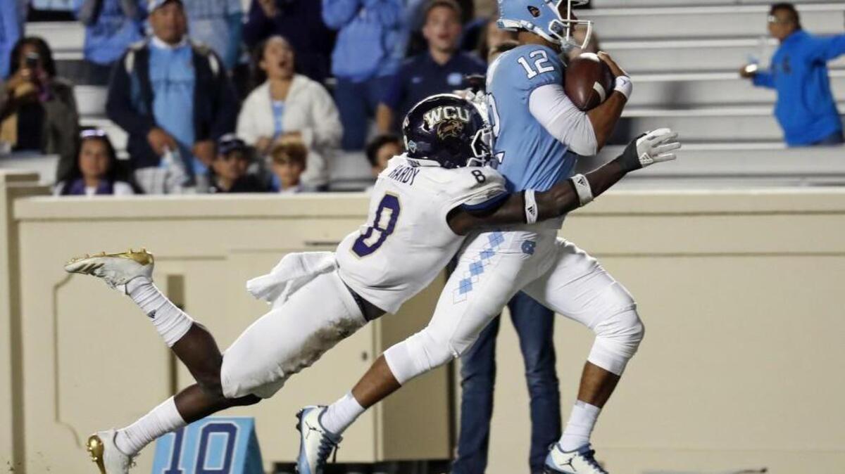 UNC's Chazz Surratt (12) drags WCU's Tra Hardy (8) into the end zone as he scores a TD during the fourth quarter of an NCAA college football game played between the UNC Tar Heels and the Western Carolina Catamounts at Kenan Stadium in Chapel Hill, NC, on Nov. 18, 2017.