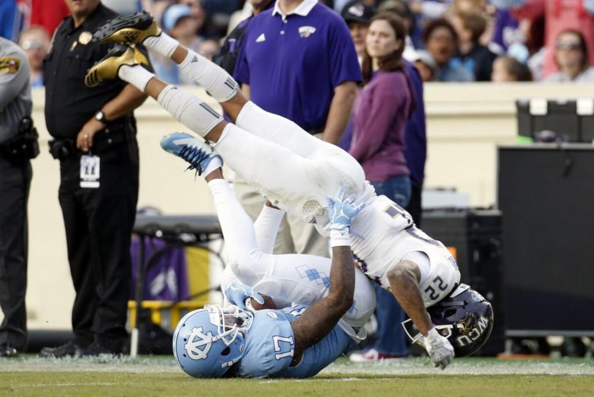 UNC’s Anthony Ratliff-Williams (17) and WCU’s JerMichael White (22) tumble after Ratliff-Williams made a fingertip catch for a long gain during the second quarter.