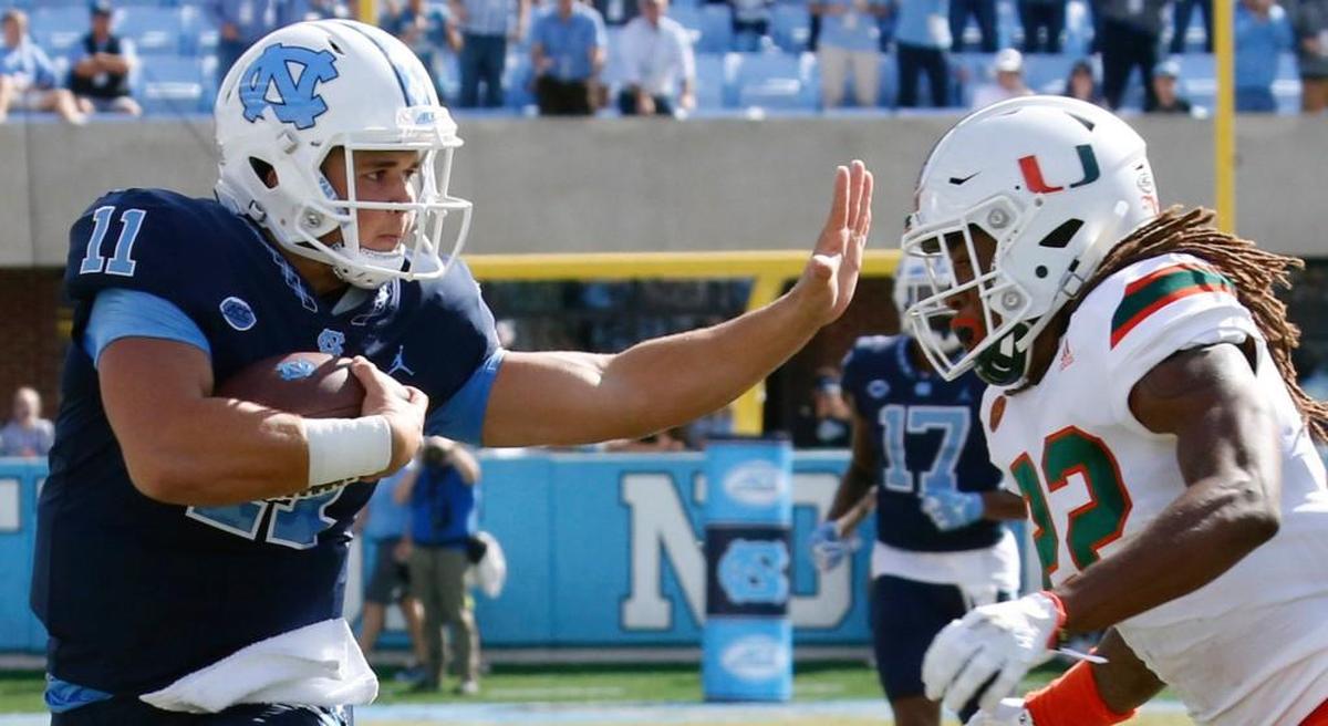 UNC's Nathan Elliott (11) stiff-arms Miami's Sheldrick Redwine (22) as he runs toward the end zone after catching a pass during the first quarter.