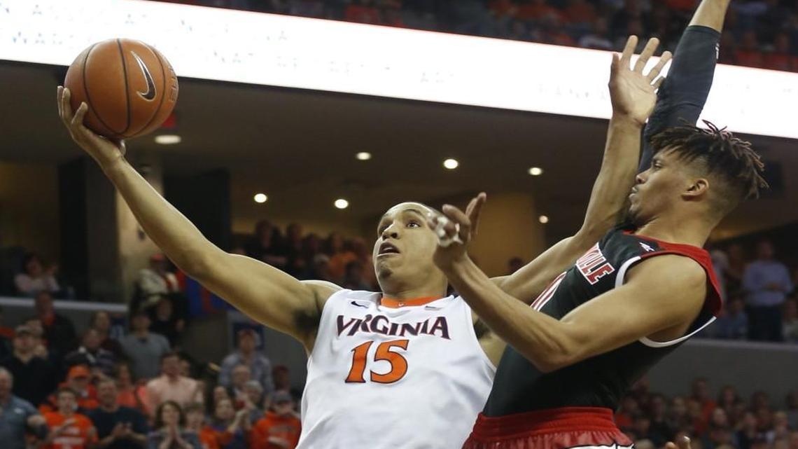 Virginia’s Malcolm Brogdon fends off Louisville’s Damion Lee during the game in Charlottesville on Saturday,.