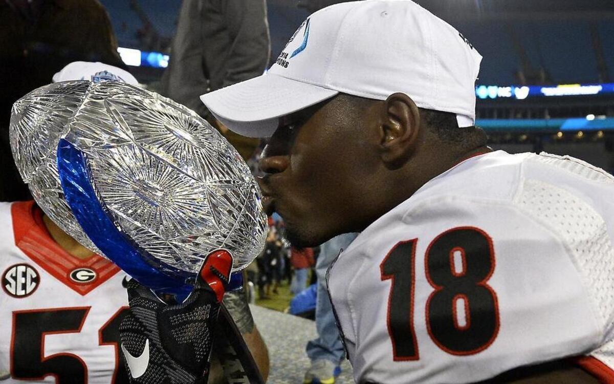 
Georgia Bulldogs split end Jonathon Rumph (18) kisses the championship trophy following the team's victory over the Louisville Cardinals in the Belk Bowl at Bank of America Stadium in Charlotte, NC on Dec. 30, 2014. The Bulldogs defeated the Cardinals 37-14.
