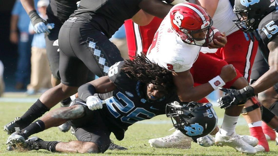 N.C. State quarterback Jalan McClendon (2) knocks off the helmet of North Carolina safety Dominquie Green (26) as he is tackled during the first half of the Wolfpack’s game against UNC at Kenan Stadium on Friday, Nov. 25, 2016.