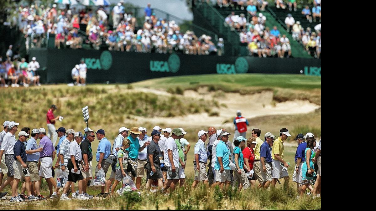 
Crowds of fans cross the 13th fairway Friday morning. Players began play at Pinehurst No. 2 during the second round of the US Open on Friday June 13, 2014 in Pinehurst, N.C. 
