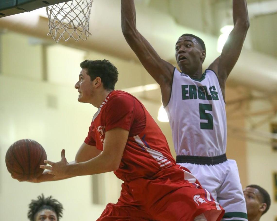 Sanderson's Jacob Feinstein (50) has to creative on his way to basket as Enloe's Moses Wright (5) crowds the airspace.