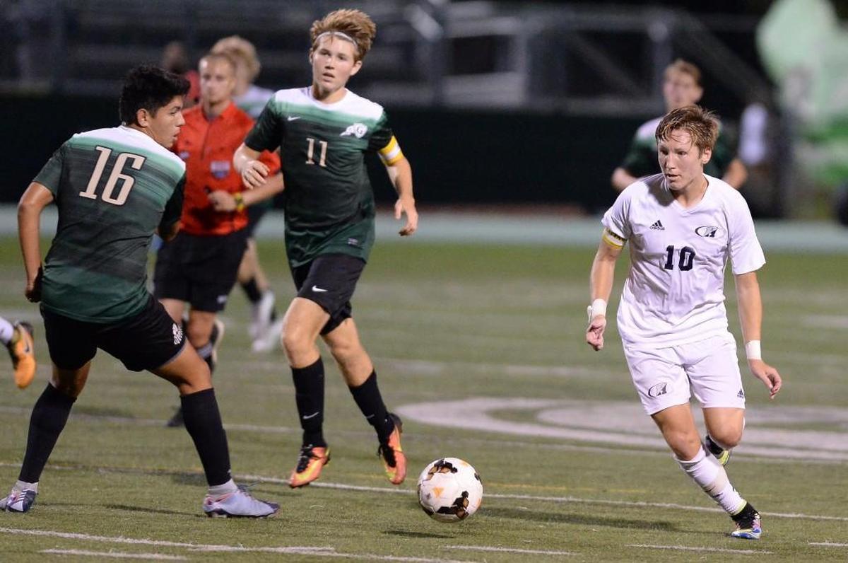 Trevor Berk (10) of Heritage dribbles against Alex Contreras (16) and Jackson Hollenbach (11) of Cardinal Gibbons. The Heritage Huskies visited the Cardinal Gibbons Crusaders in the Wake County Cup championship high school soccer game on Sept. 23, 2017.