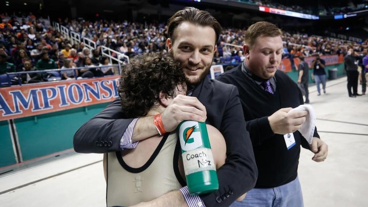 Holly Springs wrestling coach Nick Nosbisch (center) embraces Cam Devers after Devers became the school’s first wrestling state champion. Photo from the NCHSAA State Wrestling Championships in Greensboro on Saturday, February 20, 2016.