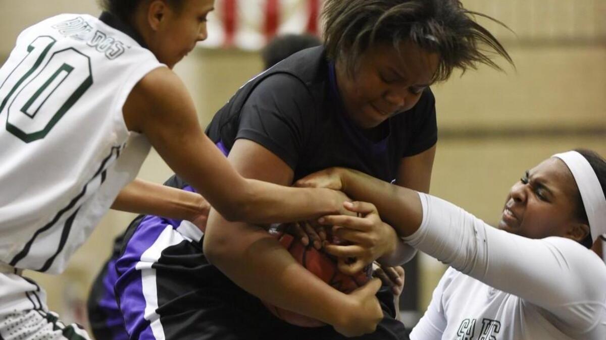 Southeast Raleigh’s Nevaeh Haddock (10) and Tamia Hicks (32) fight for the ball with Riverside’s Ajeya Murden-Boggan (30).