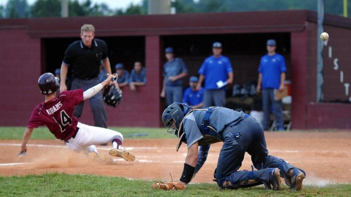 Green Hope's Kohl Abrams (14) slides into home as East Wake catcher Chase Brantley tries to stop a wide throw during the NCHSAA second round baseball playoff game in Cary on Thursday, May 11, 2016. Green Hope won 1-0 in a rain-shortened game.