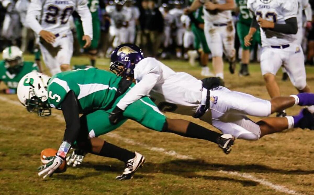 Cary's Isaiah Gibbons (5) tries to recover a fumble while Holly Springs' Yavel Morris, right, tries to hold him back during Holly Springs' football game at Cary on Friday, October 30, 2015.