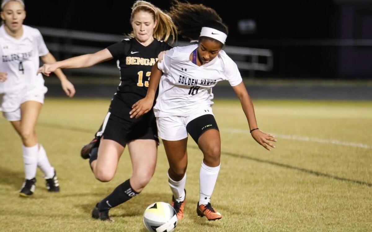 Holly Springs' Shadae Nicholas (18) dribbles as Fuquay's Maddie Smith (13) dives in for a tackle during Fuquay-Varina's soccer match at Holly Springs on Wednesday, March 8, 2017. Holly Springs won the game 3-0.