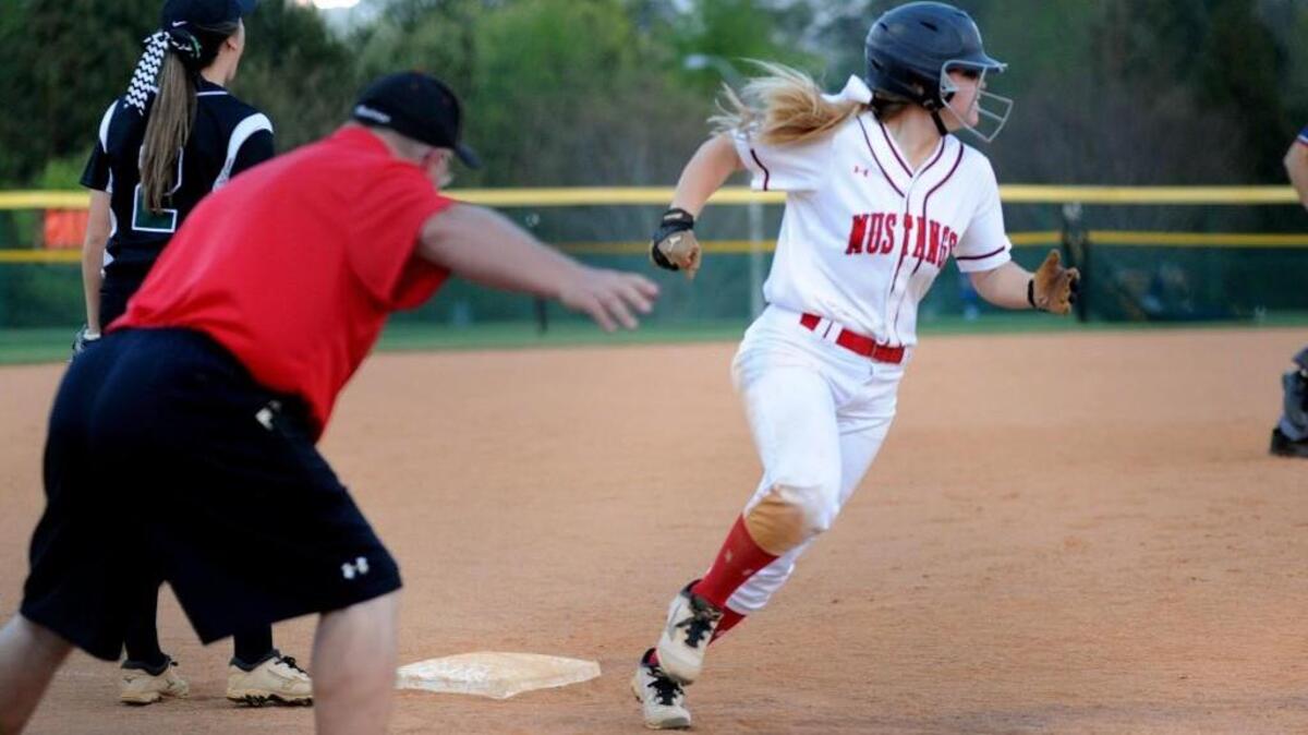 Middle Creek coach Robbie Wray (left) sends Lily Morris home during the softball game against Green Hope, which was played in Cary on March 24, 2016. Middle Creek won 10-0 in 6 innings.