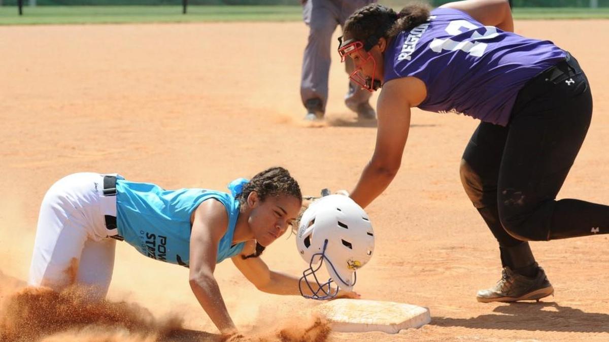 Region 3's Nadia Blevins (left) loses her helmet as she slides into third base safely under the tag by Region 4's Alexis Blackwell during the softball games at the State Games in Cary on Wednesday, June 22, 2016. Region 3 won 12-2.