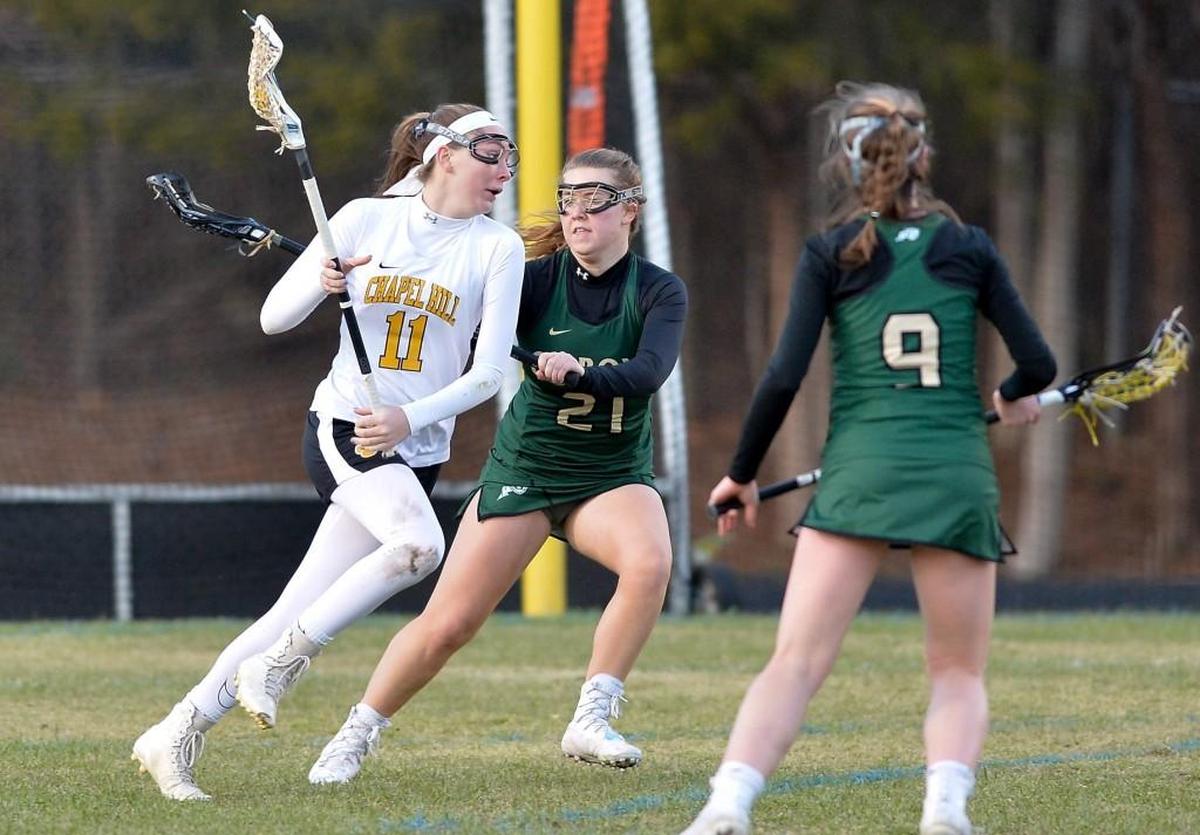 Shannon Wulff (11) of Chapel Hill moves the ball against Caroline Paquin (21) and Ella Reaves Vaughan (9) of Cardinal Gibbons. The Chapel Hill Tigers played the Cardinal Gibbons Crusaders in Chapel Hill, N.C. on Thursday, March 16 2017. Cardinal Gibbons won 18-2.