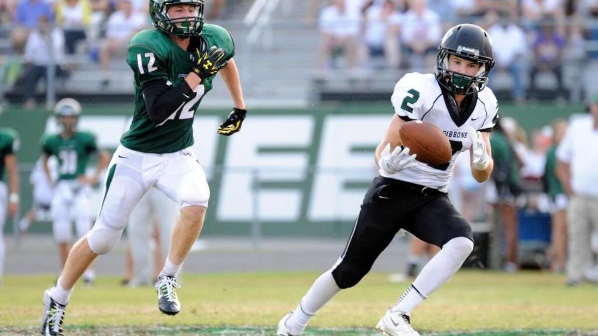 
Cardinal Gibbons’ Sean Nalesnik (2) catches a pass while pursued by Green Hope's Matt Duckworth (12). The Cardinal Gibbons Crusaders football team played the Green Hope Falcons in Cary on Friday, August 22, 2014. Green Hope won 24-23.
