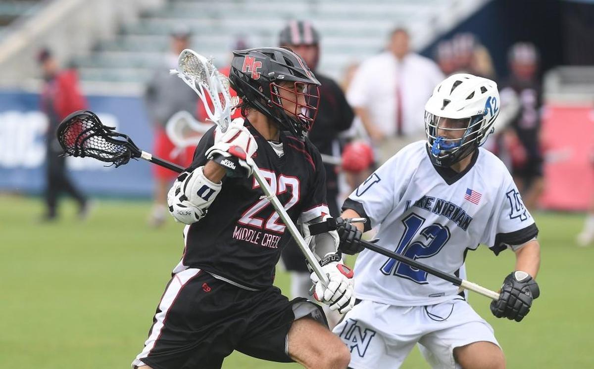 Owen Caputo (22) of Middle Creek carries the ball against Brandon Garcia (12) of Lake Norman. The Middle Creek Mustangs played the Lake Norman Wildcats in a boys lacrosse game that counted for the NCHSAA 4A championship at the WakeMed Soccer Park in Cary, N.C. on May 19, 2018.