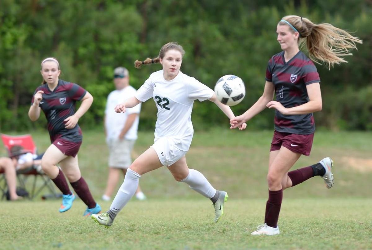 Isabel Pearce (22) of Woods Charter connects with a pass against the defense from Madison Fournier, left, and Ilaina Hertzig, right, of East Wake Academy. The Woods Charter Wolves played the East Wake Academy Eagles in a girls soccer game that took place in Chapel Hill, N.C. on Monday, May 1 2017. Woods Charter won 3-0.