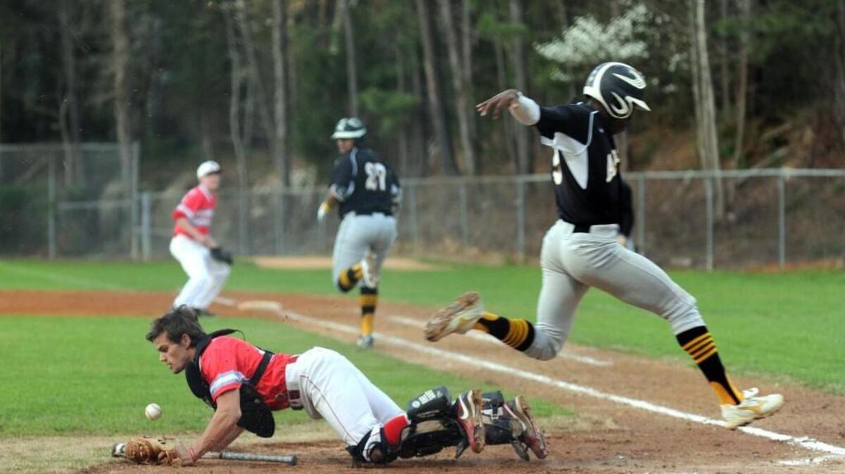 Apex's Estaban Valencia (right) is safe at home on a dropped throw by Sanderson catcher Ryan Baldy during the championship game of the Wake County Invitational.
