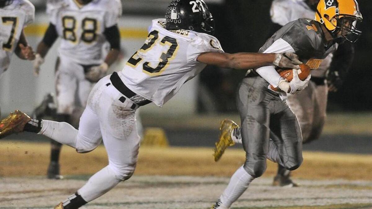 Clinton’s Rayquan Faison (23) reaches out to grapple Bunn quarterback Quenten Wright (7) as he runs for yardage. The Bunn Wildcats took on the Clinton Dark Horses in the NCHSAA 2A East Final at Bunn, N.C. on Friday December 4, 2015.