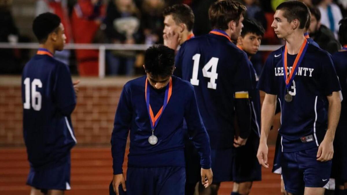 Lee County's Osciel Dominguez hangs his head in disappointment after the medal ceremony following the NCHSAA 3A State Championship between Lee County and Weddington on Saturday, November 21, 2015. Weddington won the game 2-0.
