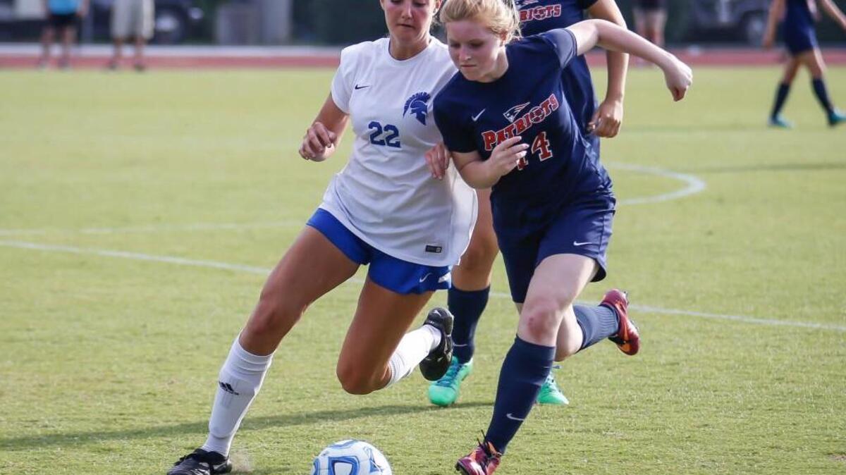 Franklin Academy midfielder Taylor Kassay (14) dribbles through the pressure applied by Community School of Davidson's Julia Grainda (22) during the NCHSAA 1A State Championship girls soccer game between Community School of Davidson and Franklin Academy in Raleigh on Saturday, May 28, 2016. Community School of Davidson won the game 5-1.