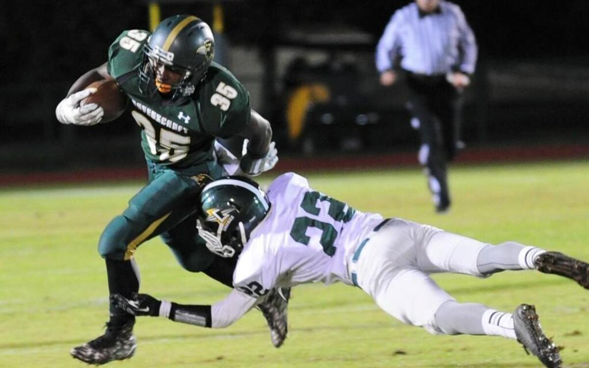 Ravenscroft's Donathan Muldrow (35) breaks the tackle of Christ School's Gabe Blevins (22) during the NCISAA championship football game, which was played on Friday, November 20, 2015 in Raleigh.