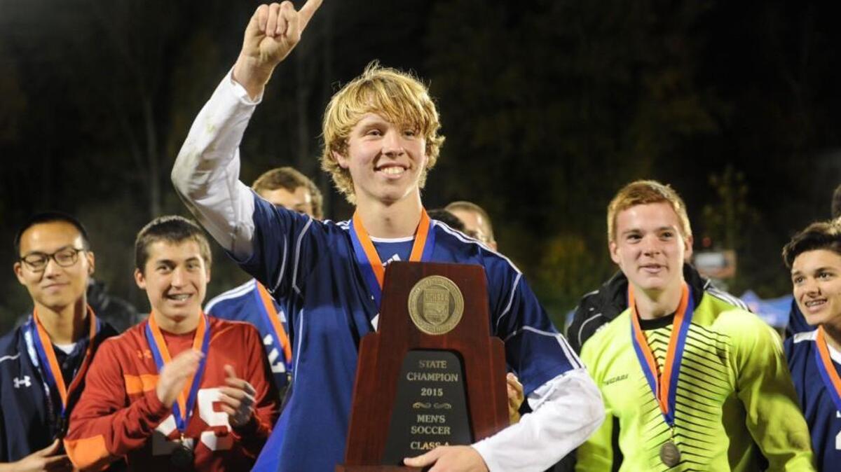 Nick Hughes accepts the Championship trophy on behalf of Franlkin Academy in the win over Community School of Davidson after the NCHSAA 1A boys soccer championship game, which was played on Saturday, November 21, 2015 in Raleigh. Franklin Academy won 3-1.